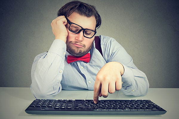 man sitting at computer keyboard with crooked glasses