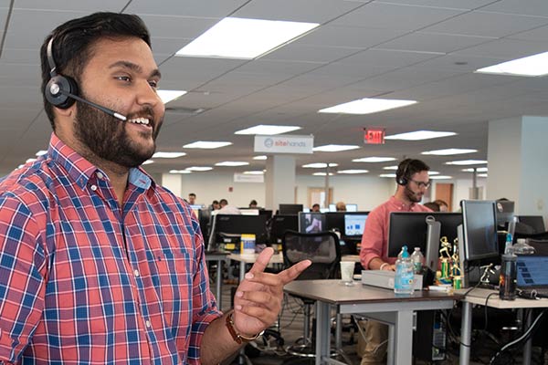 male bearded sales rep wearing headset and blue and red plaid shirt