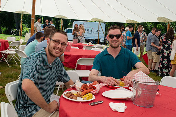 two employees eating lobster and corn at a company party