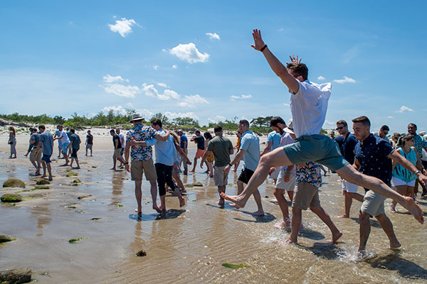 group at a company party on the shore with one man jumping