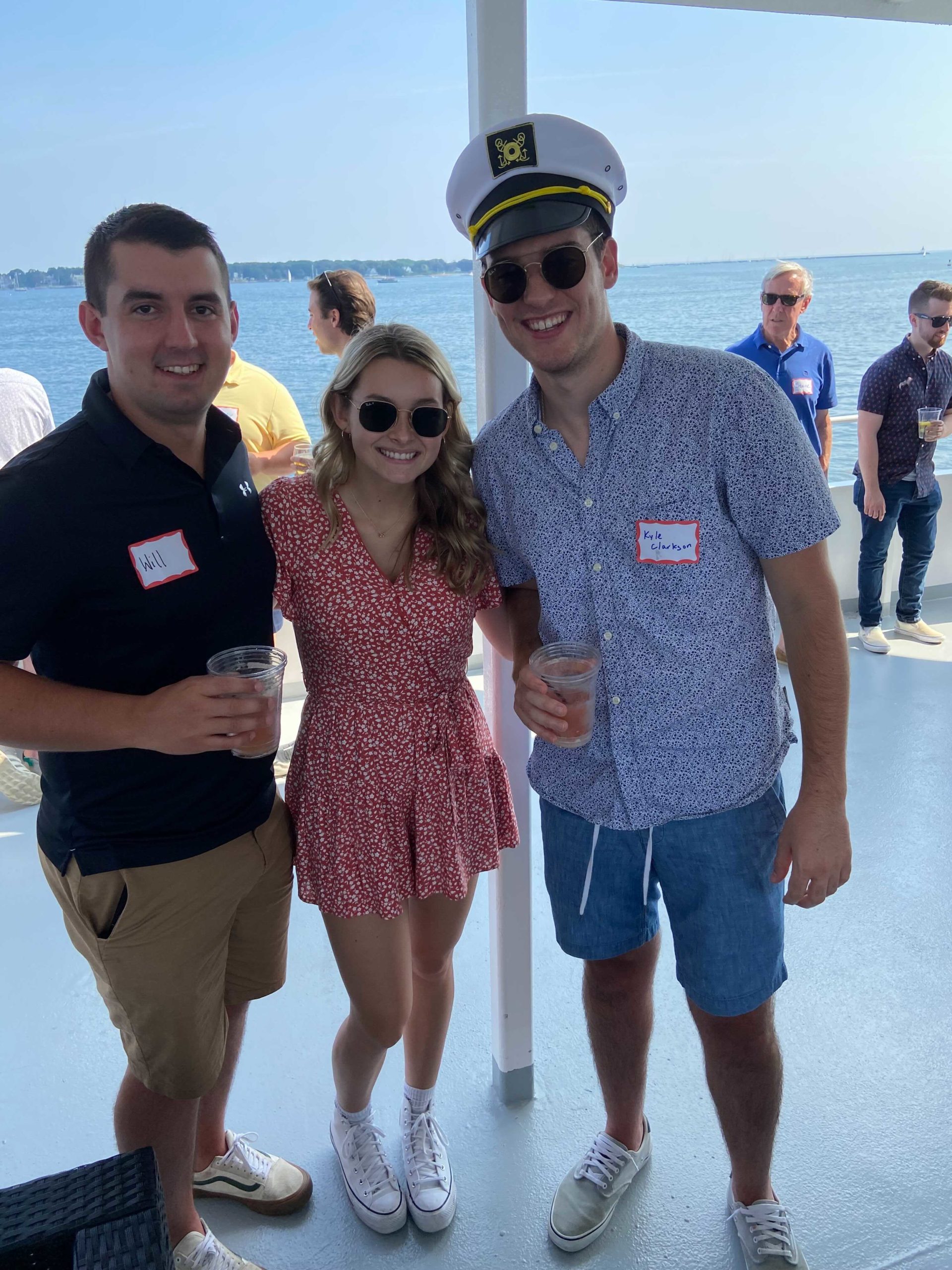 three Reveneer employees on a boat with one wearing a captain's hat