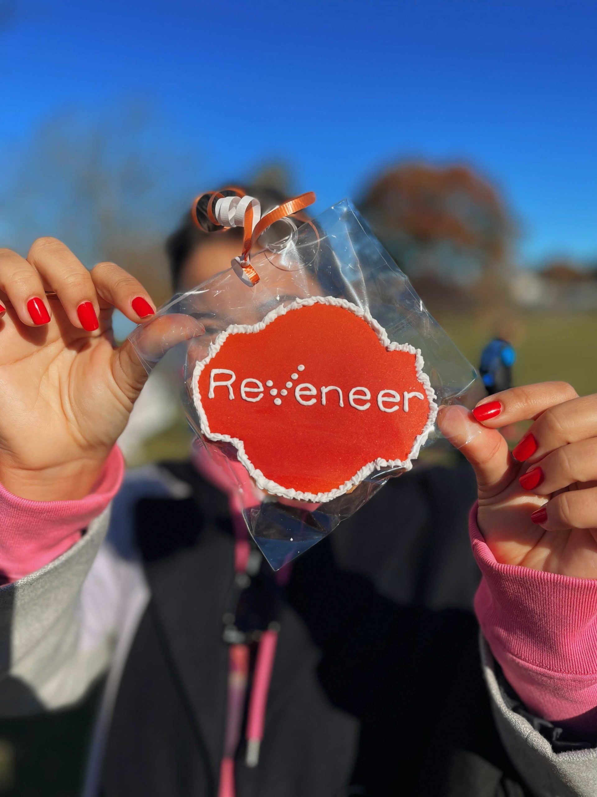 Reveneer employee holding a Reveneer logo cookie
