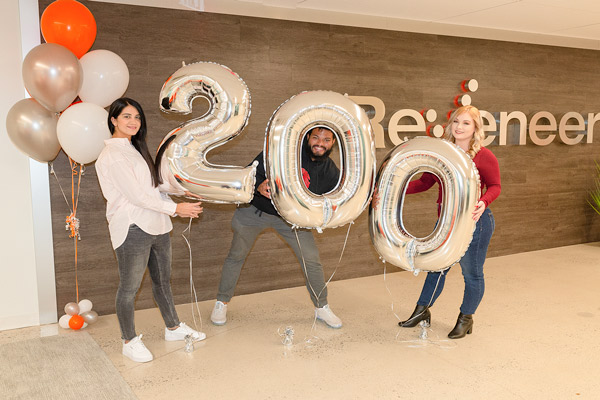 three employees holding balloons to represent 200th employee