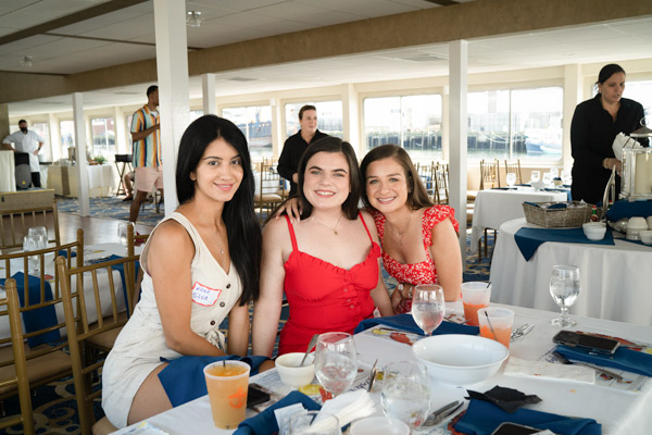 three female Reveneer employees sitting at a table on a boat