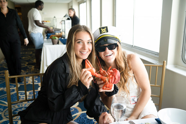 Two female Reveneer employees on a boat eating lobster