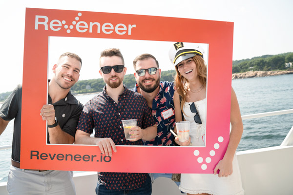 Reveneer employees on a boat standing inside a Reveneer photo frame
